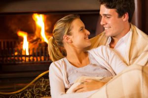 couple sitting in room warmed by fireplace and clean HVAC air ducts